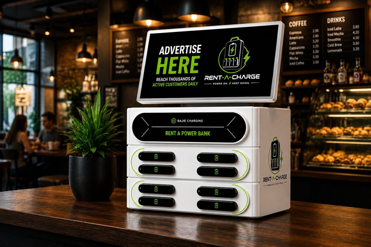 White phone charging kiosk with digital display on a cafe counter, featuring multiple charging ports and Advertise Here banner
